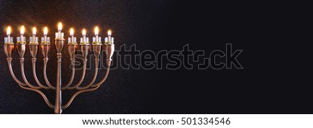 Low key Image of jewish holiday Hanukkah background with menorah (traditional candelabra) and burning candles. Glitter overlay. Wide format