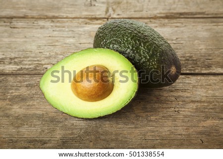 Whole and halved avocado fruit on rustic wooden background