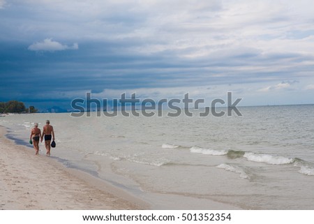 senior couple walking on the beach Storm is coming overcast