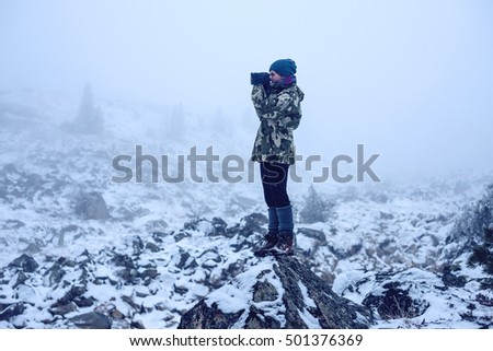 the girl in the stones with a camera, looking at nature, travel concept