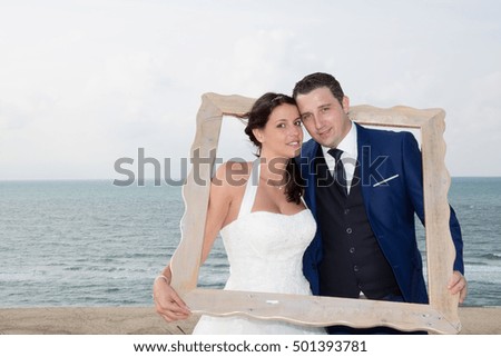 Lovely wedding couple looking through a picture frame