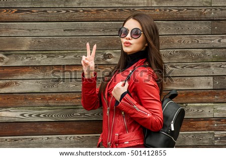 Beautiful smiling brunette woman in sunglasses blowing lips kiss over wooden background. Street fashion. Outdoors.