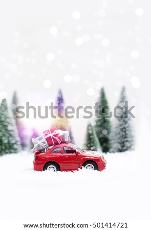 Snowy Winter Forest with miniature red car carrying a  christmas tree and presents