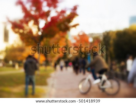 blurred background of city life. blurred red maple and the people in the park