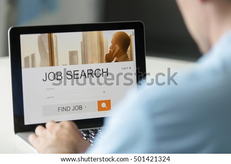 Monitor view over a male shoulder, job search title on the screen, close up. Education, business concept photo