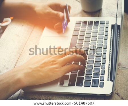 Man hand holding credit card and use laptop vintage tone.