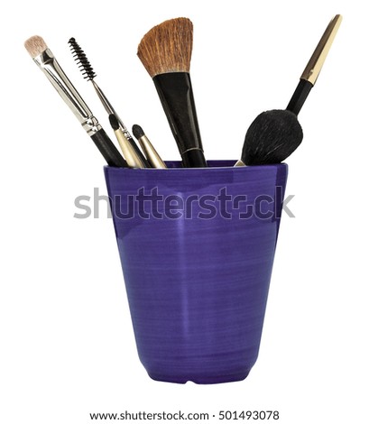 Makeup brushes and pencil in a glass, isolated on white