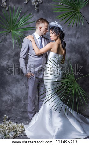 Portrait of beautiful bride standing with bridegroom against wall