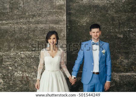 Brides hold hands near wall