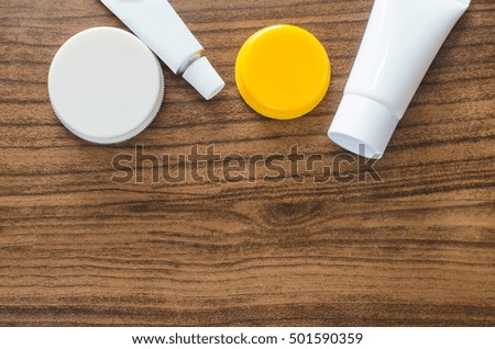 blank of white and yellow plastic bottle, tube for cosmetic container on wood board