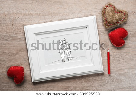 Photo frame with happy couple drawing on wooden table