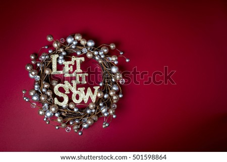 let it snow Christmas banner on rustic ring crown rim wreath red background Gold and silver ornament balls Christmas wreath
