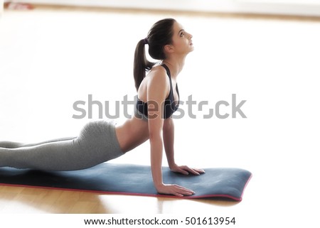 Yoga, fitness, sport, training and lifestyle concept - smiling woman stretching leg on mat in gym