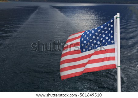American Flag on back of boat/ American Flag Water Background/ The American Flag flies behind a boat on Lake McDonald in Glacier National Park, Montana.
