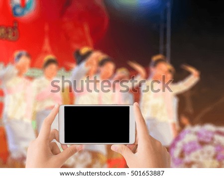 woman use mobile phone and blurred image of thai classical dance show , asian girls with thai dance show on the stage in chiang mai , thailand