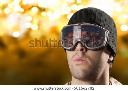 skier looking for a snowy mountain on a yellow lights background.
