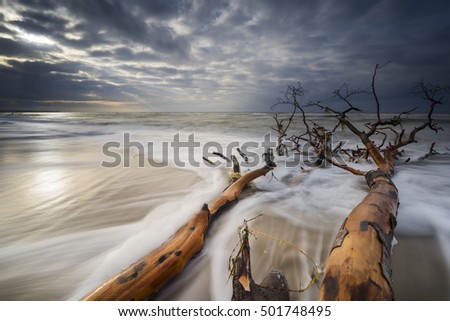 Baltic Sea at nightly light and long exposure, Undergoing sun irradiates the sea and stones in the sea water, Moving lake and foaming waves on the shore,