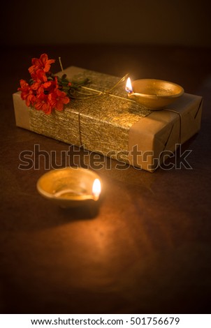 Two illuminated Indian earthen lamps and elegantly wrapped gift box and flower. Diwali is the biggest Hindu festival celebrated in India.  Royalty-Free Stock Photo #501756679