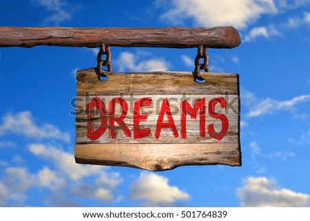 Dreams motivational phrase sign on old wood with blurred background