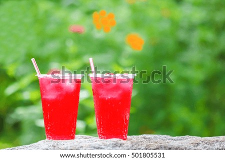 red water with ice in cups on nature for thirst in holiday