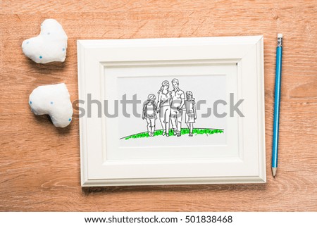 Photo frame with happy family drawing on wooden table
