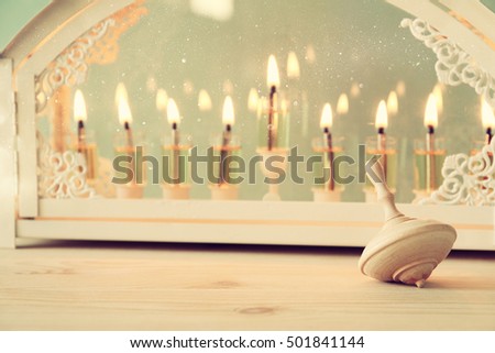 Selective focus image of jewish holiday Hanukkah with menorah (traditional Candelabra) and wooden dreidel (spinning top). Vintage filtered