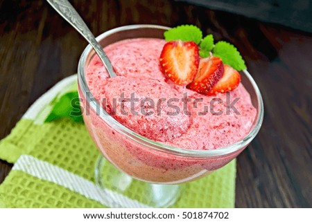 Jelly air strawberry in a glass bowl with a spoon, mint on a green towel on a background of wooden boards