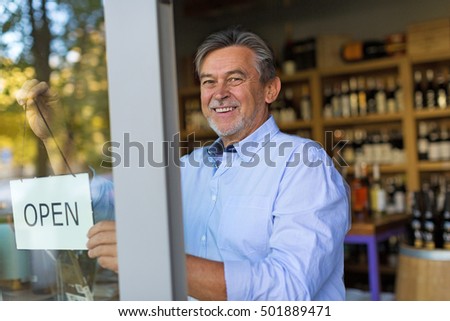 Wine shop owner holding open sign
