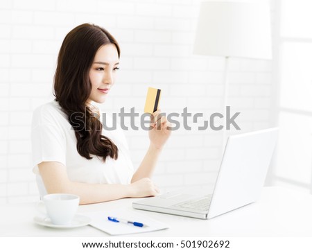 happy young woman showing credit card and laptop 