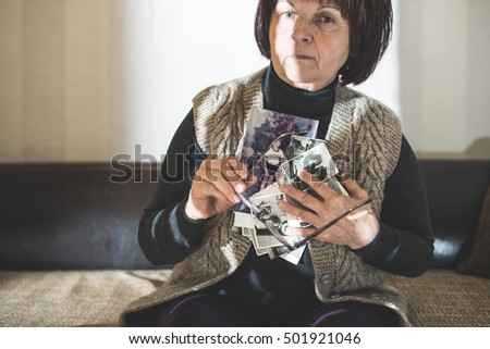 Senior woman watching old photos. Sadness