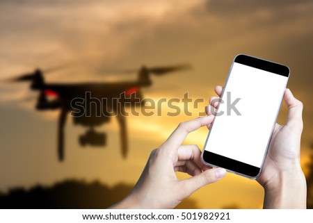 Hand using smart phone on white screen and blur background with flying drone.