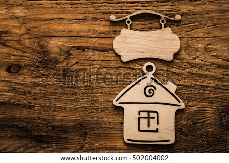 House shape hanging wooden sign and signboard isolated on a wooden background