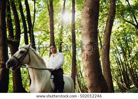 The groom riding a horse on the forest