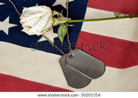 dried rose with military dog tags on flag