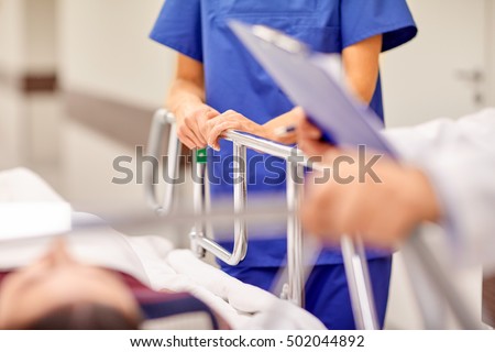 profession, people, healthcare, reanimation and medicine concept - medics or doctors carrying unconscious woman patient on hospital gurney to emergency room Royalty-Free Stock Photo #502044892
