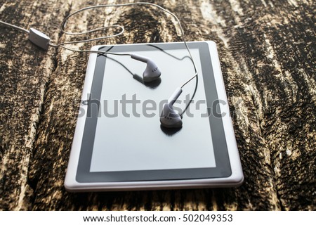 tablet and headphones on wooden background
