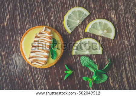 lemon tart desert with cream decoration and mint leaves on wooden table background