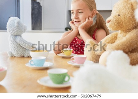 Girl having tea party with soft toys