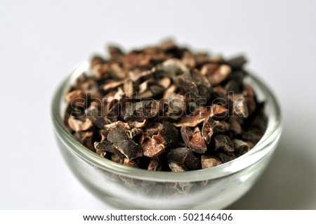 Raw cocoa bean nibs (Theobroma cacao) in bowl isolated on white background

