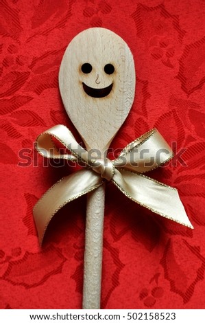 Smiling wooden spoon with a golden bow on a seasonal background