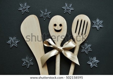Three cooking wooden spoons on black holiday  background with snow flakes