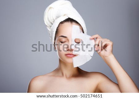 Girl with half rended white mask. Model pulling away mask from her face. Closed eyes. Head and shoulders, studio, indoors Royalty-Free Stock Photo #502174651