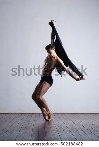 Athletic ballet dancer in a perfect shape performing dramatic dance.
