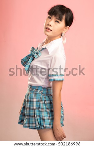 Young cute asian student woman  in uniform on pink background