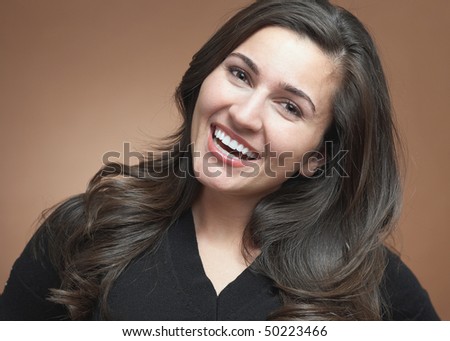Beautiful young woman laughing on brown background