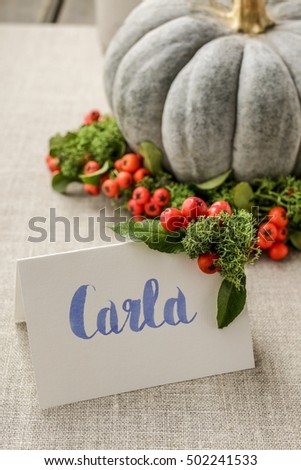 Green pumpkin decorated with red berries (cotoneaster horizontalis) and green moss wreath. Wedding vignetted with handwritten name Carla.