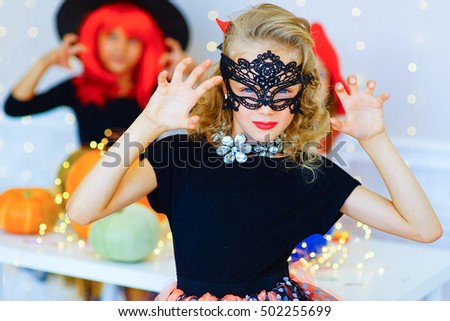 Happy group of children in costumes during Halloween party playing around the table with pumpkins and bottle of potion