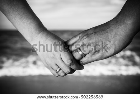Hands and hearts together.Close-up of loving couple holding hands at the sea