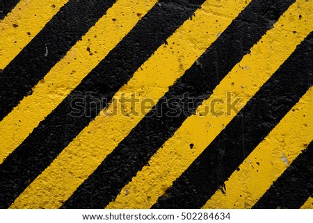 Black and yellow diagonal lines on a concrete background