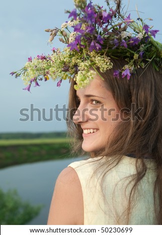 long-haired teen girl  in flower chaplet against river